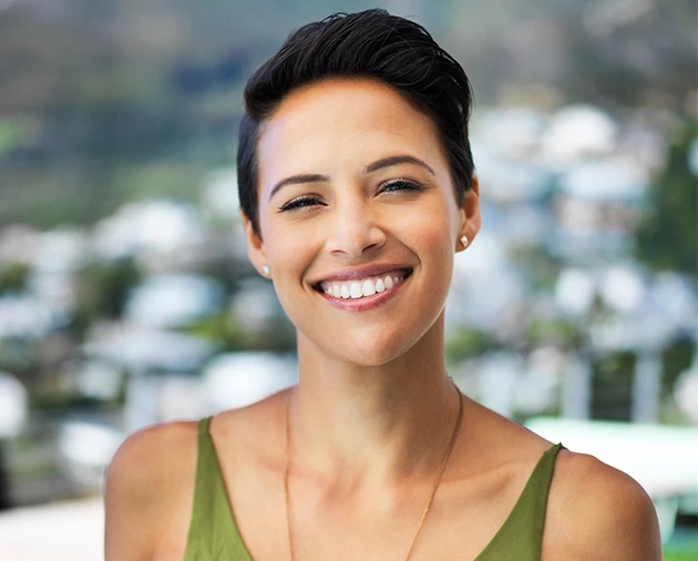 Smiling woman with a bright smile and short hair, showcasing dental health and confidence, relevant to cosmetic dentistry services.