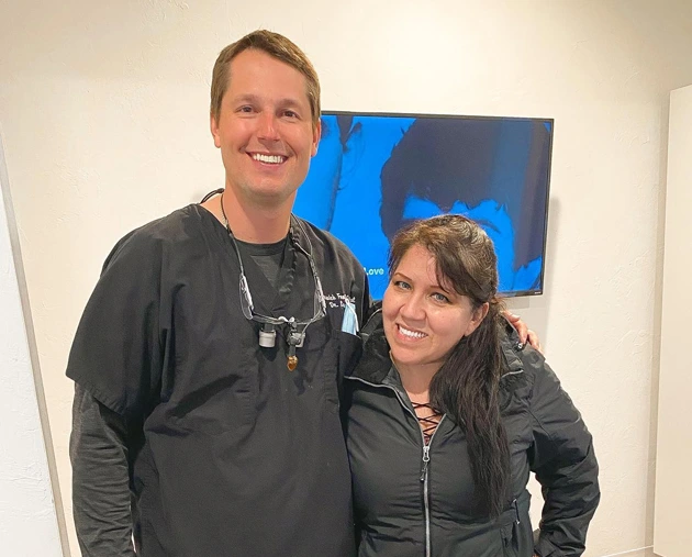 Smiling dentist in scrubs with patient in dental office, showcasing patient care and satisfaction at Warwick Dental.