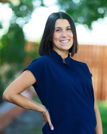 Amy Griffis, dental hygienist and social media manager at Warwick Dental, smiling in a navy shirt, showcasing her commitment to patient care and community engagement.