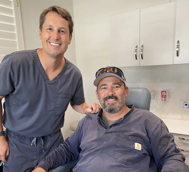 Dentist in scrubs smiling with patient in dental chair, showcasing friendly sedation dentistry experience at Warwick Dental in Oklahoma City.