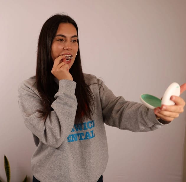 Woman checking Invisalign aligner at Warwick Dental Oklahoma City
